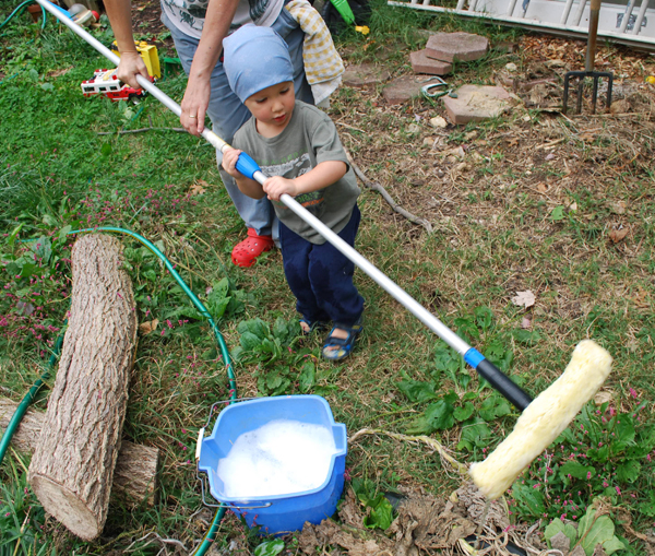 toddler helping with chores - using a long pole for window washing